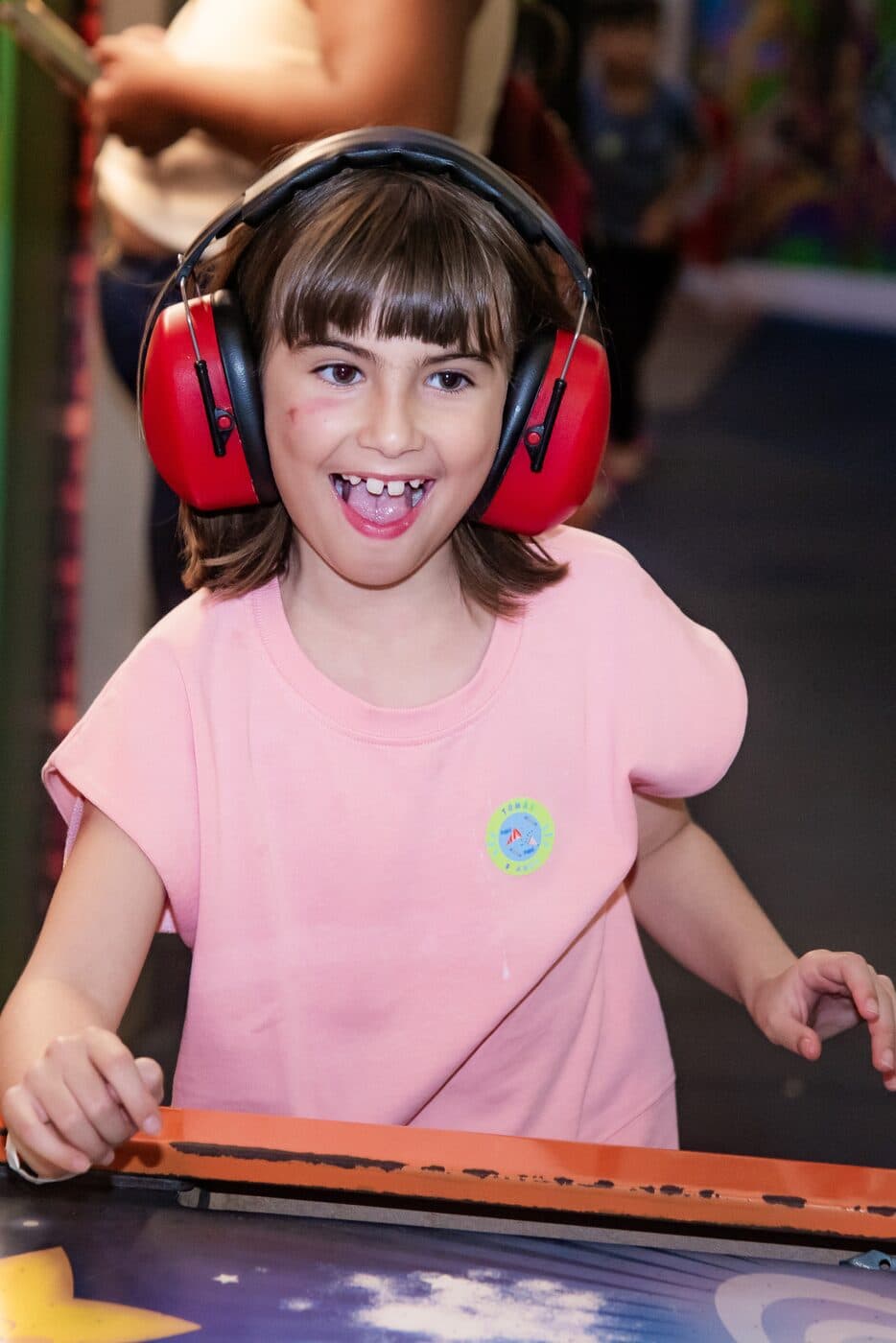 Menina sorrindo com fones de proteção em festa infantil